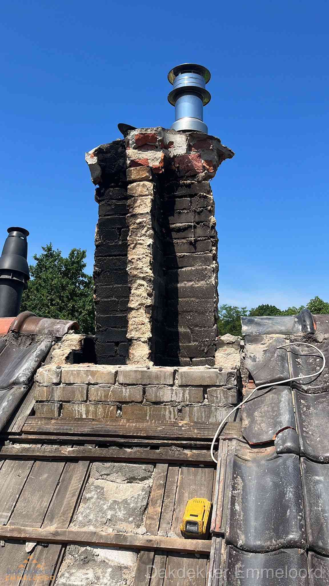 Beschadigde schoorsteen met nieuwe rookgasafvoer op oud dak in Emmeloord