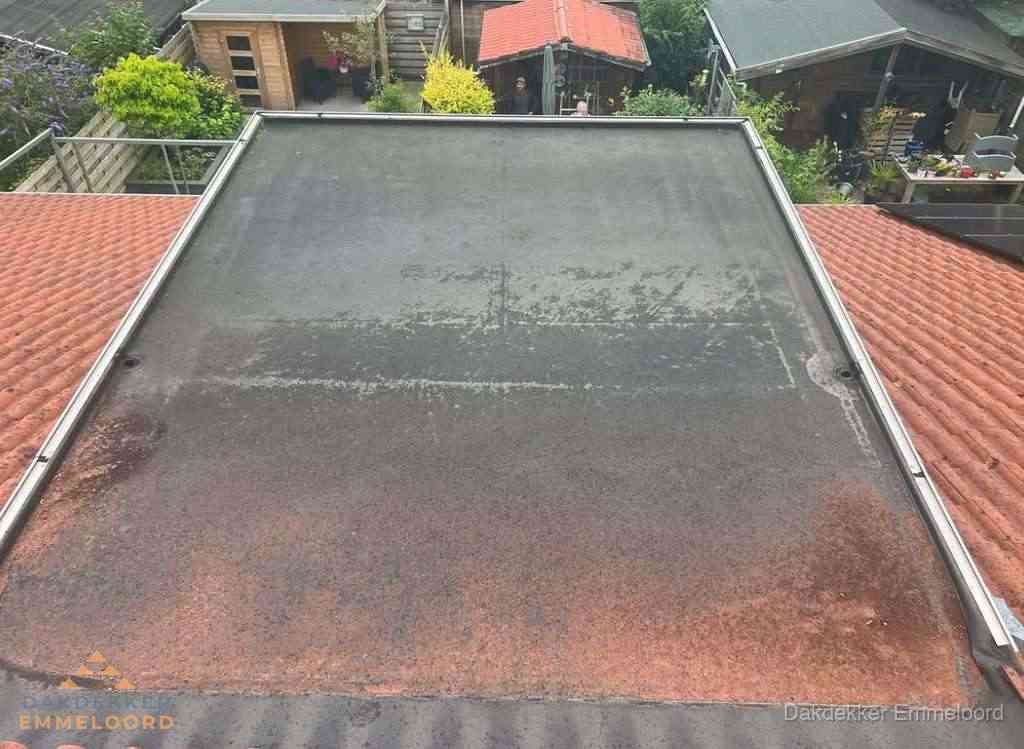Verouderd plat dak met slijtage tussen schuine daken in Emmeloord
